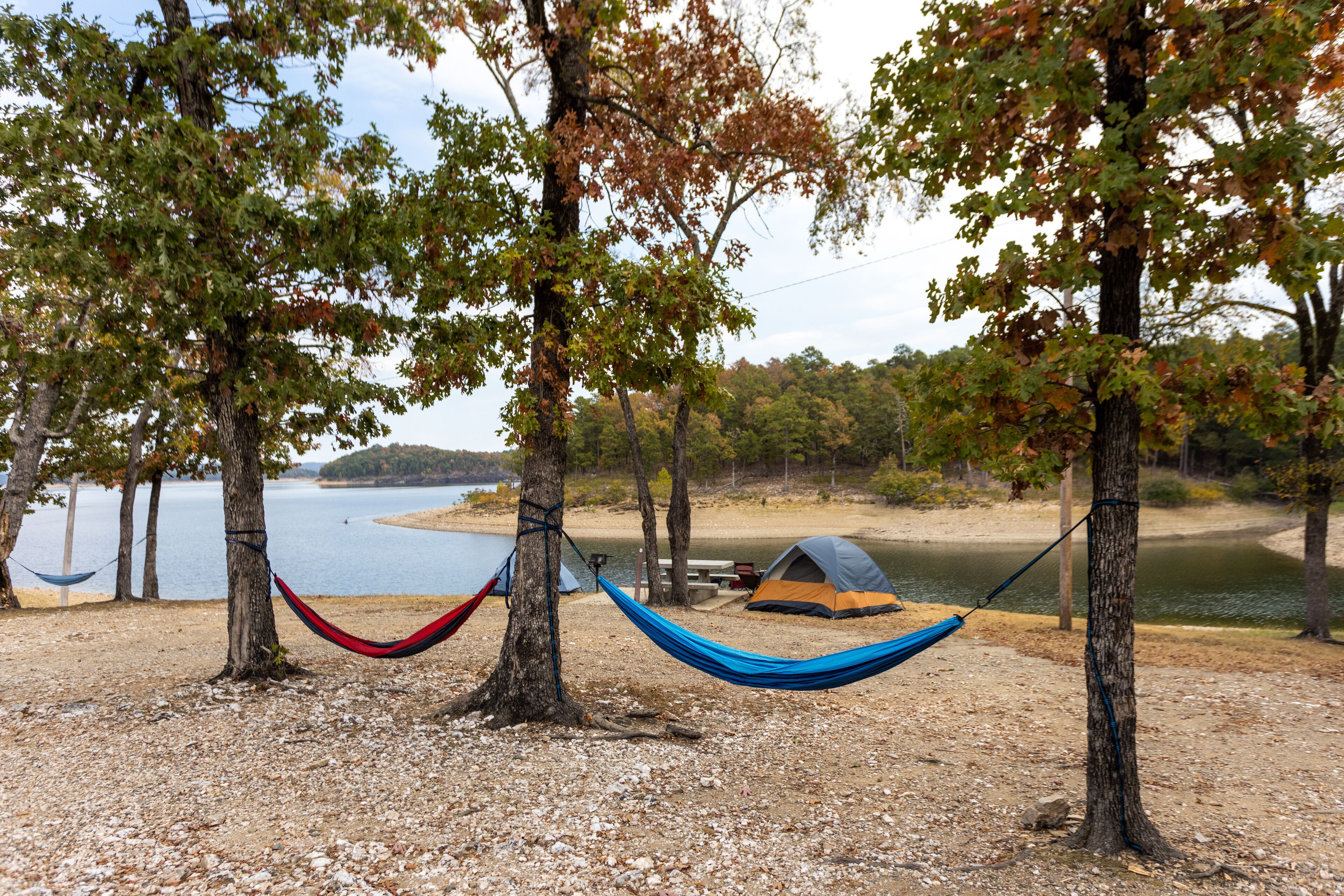 Camping tents and hammock near a beautiful lake among trees, campsite, adventure vacation concept, Broken bow lake in Oklahoma, USA.