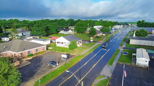 West Gentry Avenue in downtown Checotah, small town in McIntosh County, Oklahoma, mix of commercial buildings, churches, schools, residential neighborhood large houses, lush green trees, aerial
