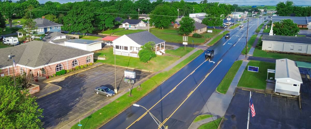 A suburban street with houses, a library, and a road.