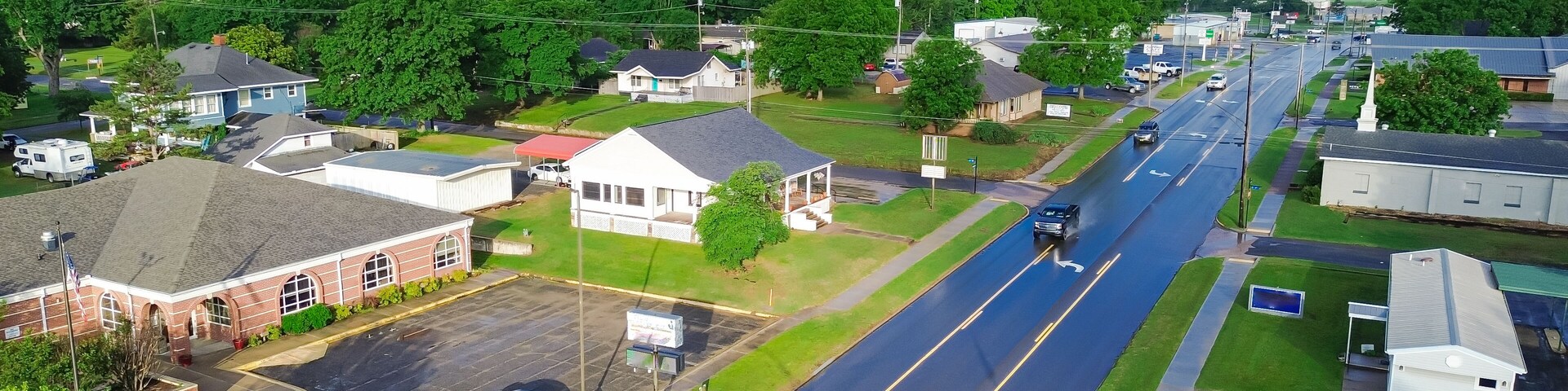 A suburban street with houses, a library, and a road.