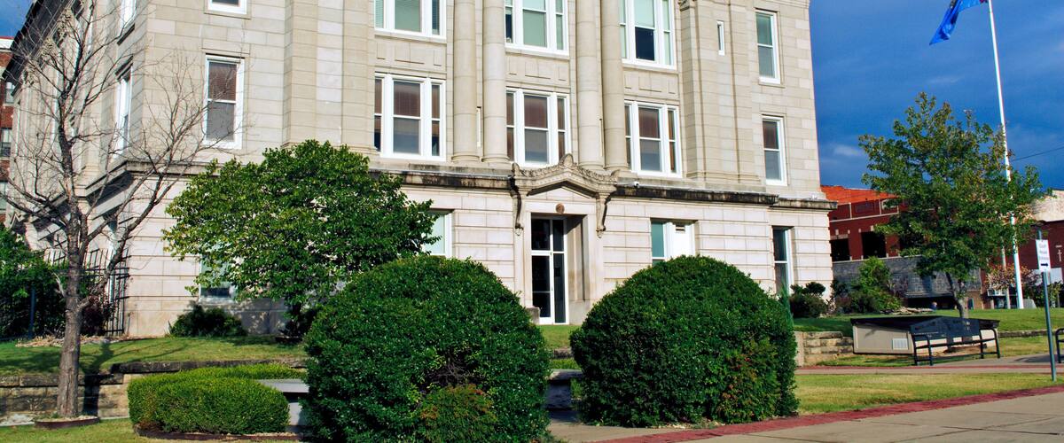 A historic building with columns, a flag, and well-maintained landscaping.