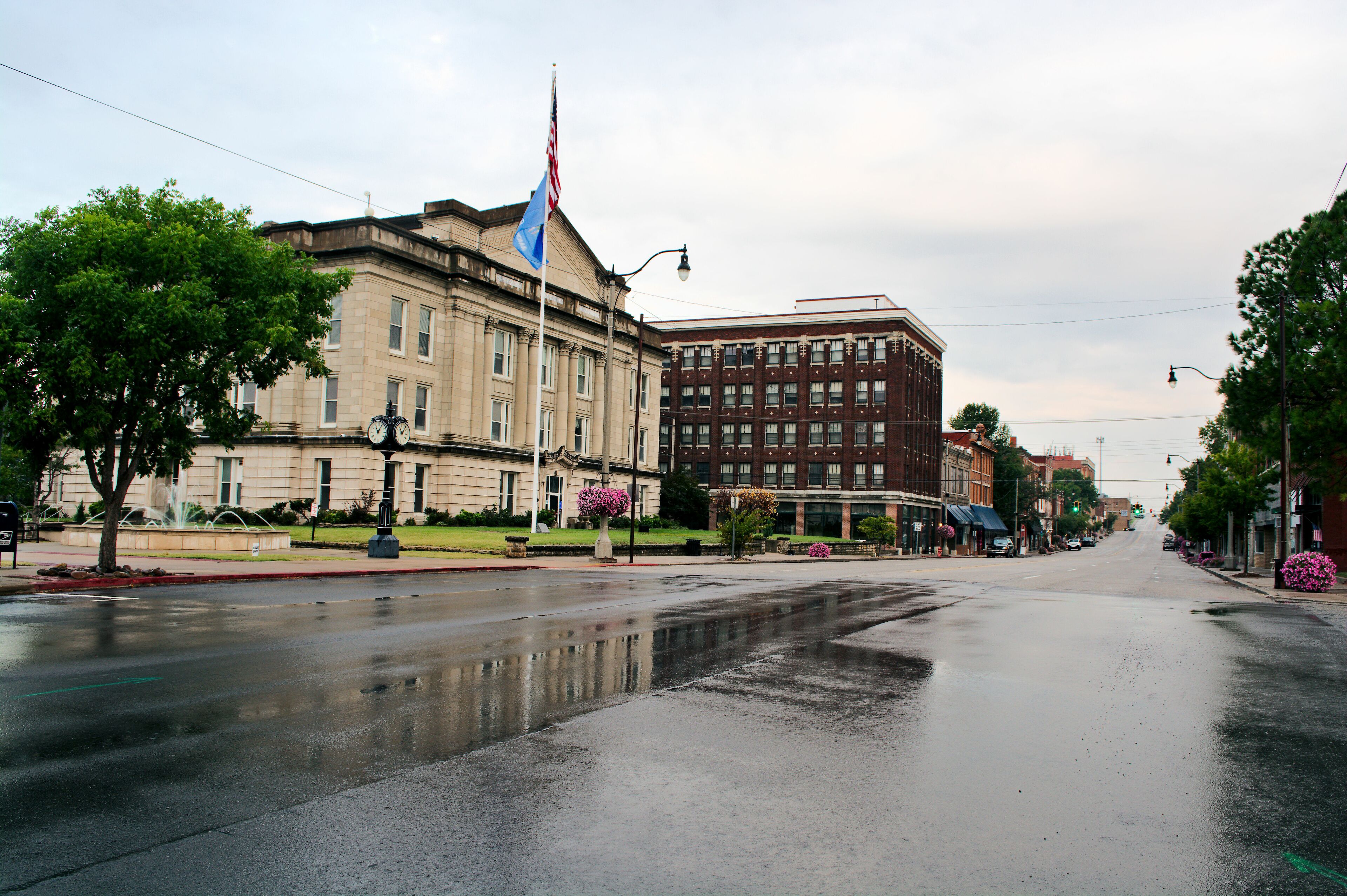 Looking west on Route 66 rainy morning Sapulpa, Oklahoma. Wet pavement of Dewey Avenue reflects the Creek County Courthouse. Small town USA.