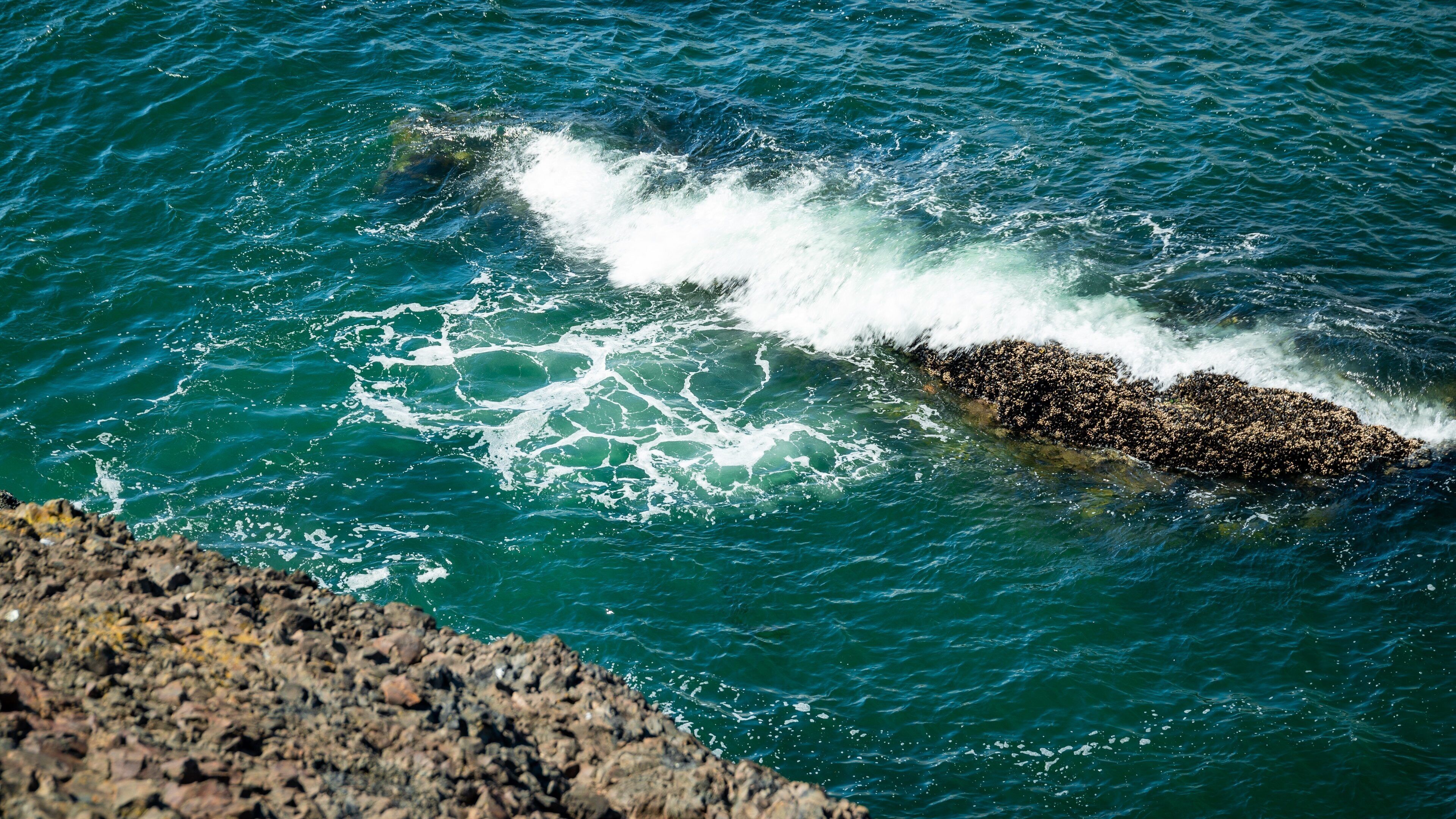 Una costa rocosa con olas rompiendo contra ella.
