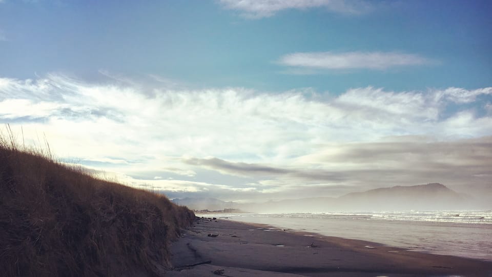 A beach with sand dunes and a cloudy sky.