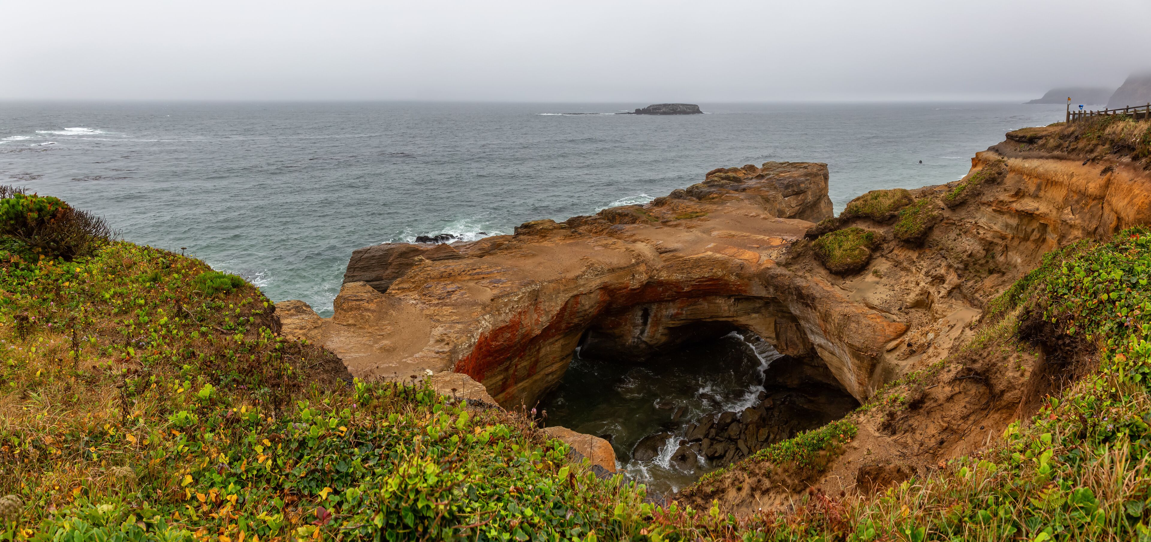 Panoramic View of Devil's Punchbowl Arch during a rainy summer day. Taken at Otter Rock, Oregon Coast, United States of America.