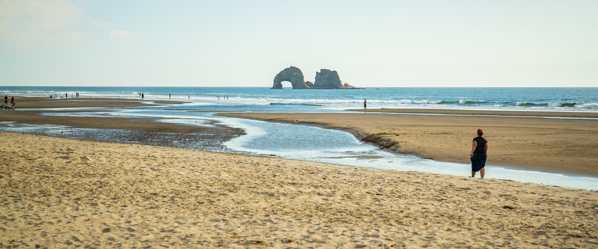 A sandy beach with a large rock formation in the distance.