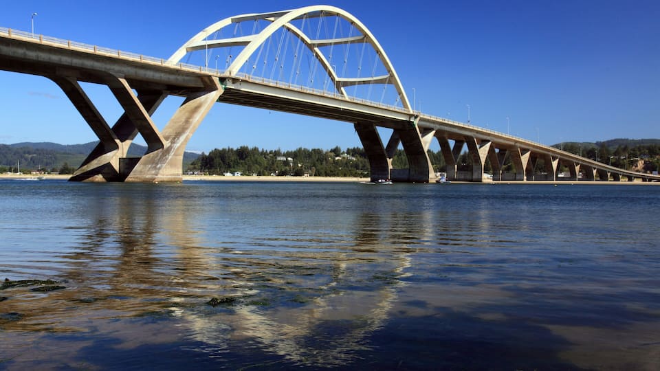 A large bridge spanning a river with a clear blue sky and calm water.