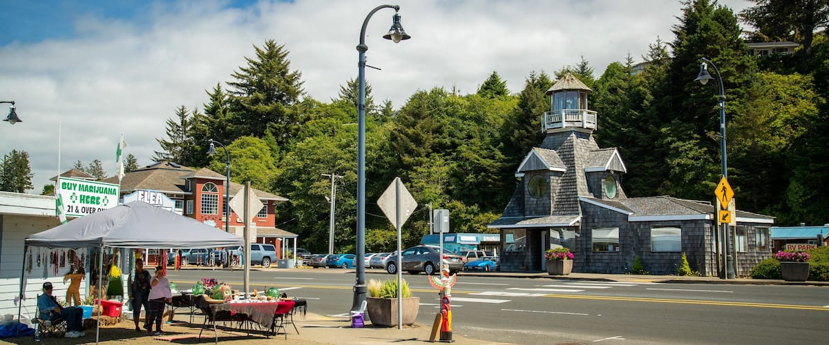 A street with a market stall, a bell tower, and RV park signs.