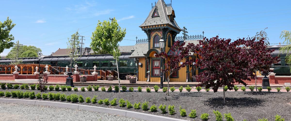 A historic train station with a distinctive tower and vintage train cars.