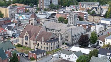 Aerial view of a grand church with its soaring tower piercing the sky above a tapestry of buildings and streets, Carbondale, Pennsylvania, United States.