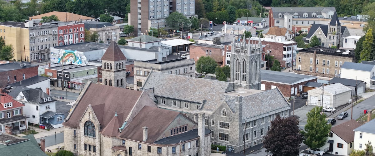 A historic church with a prominent steeple and a large mural on the side of a building.