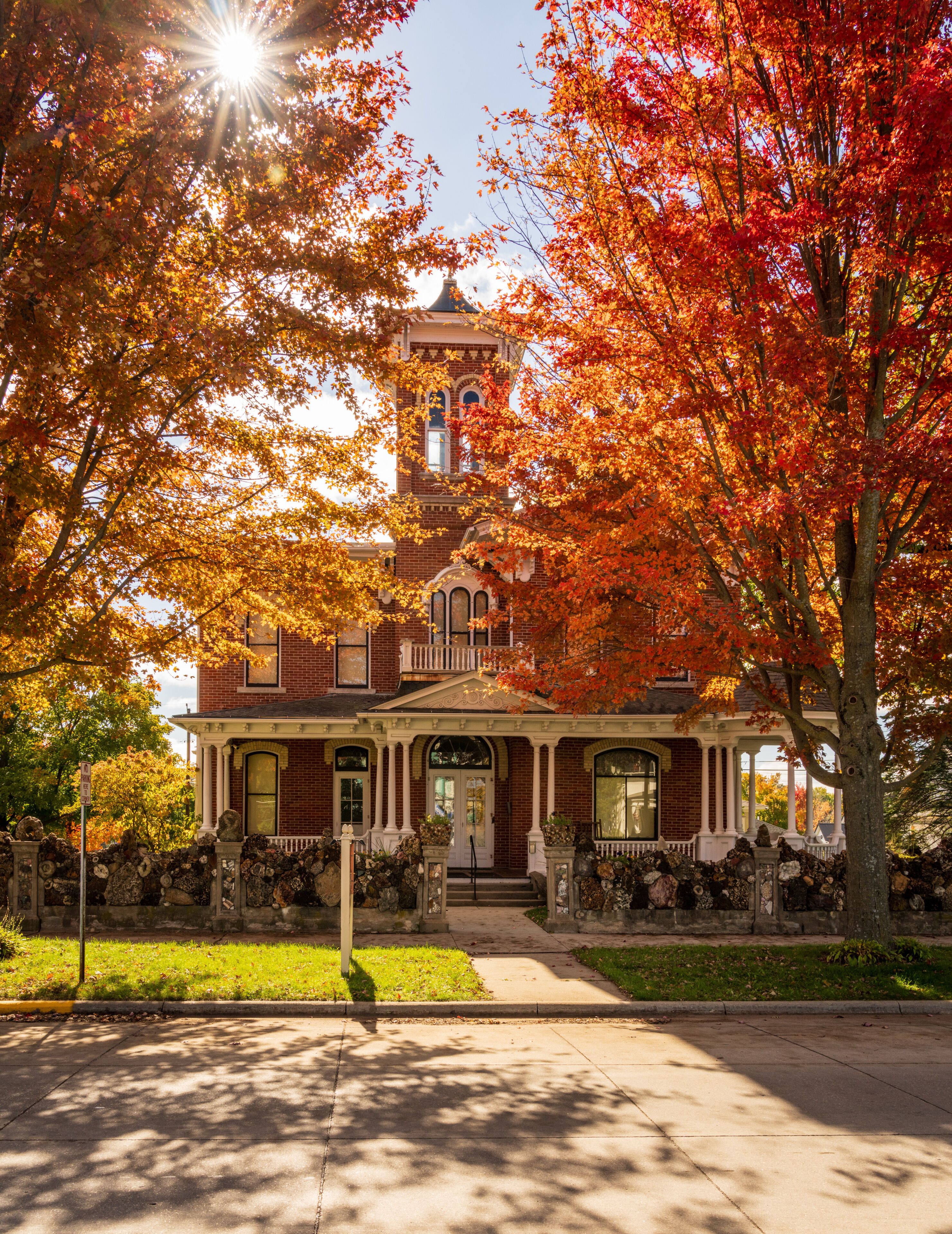 A Victorian-style house with a prominent tower, surrounded by autumn foliage.