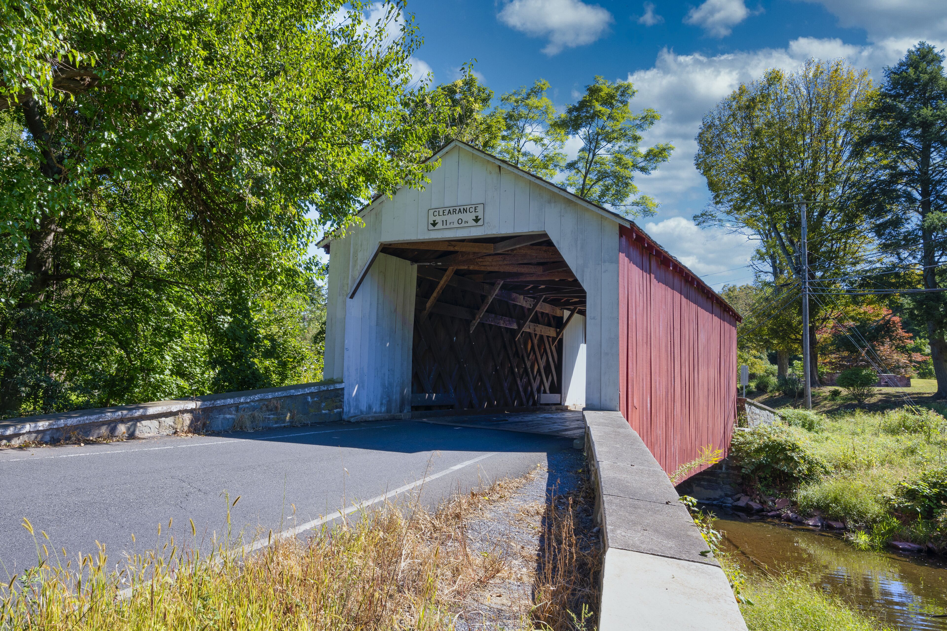A covered bridge with a sign that reads "Clearance 11 ft. 0 in."