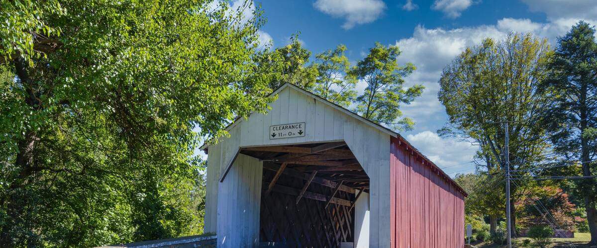 A covered bridge with a sign that reads "Clearance 11 ft. 0 in."