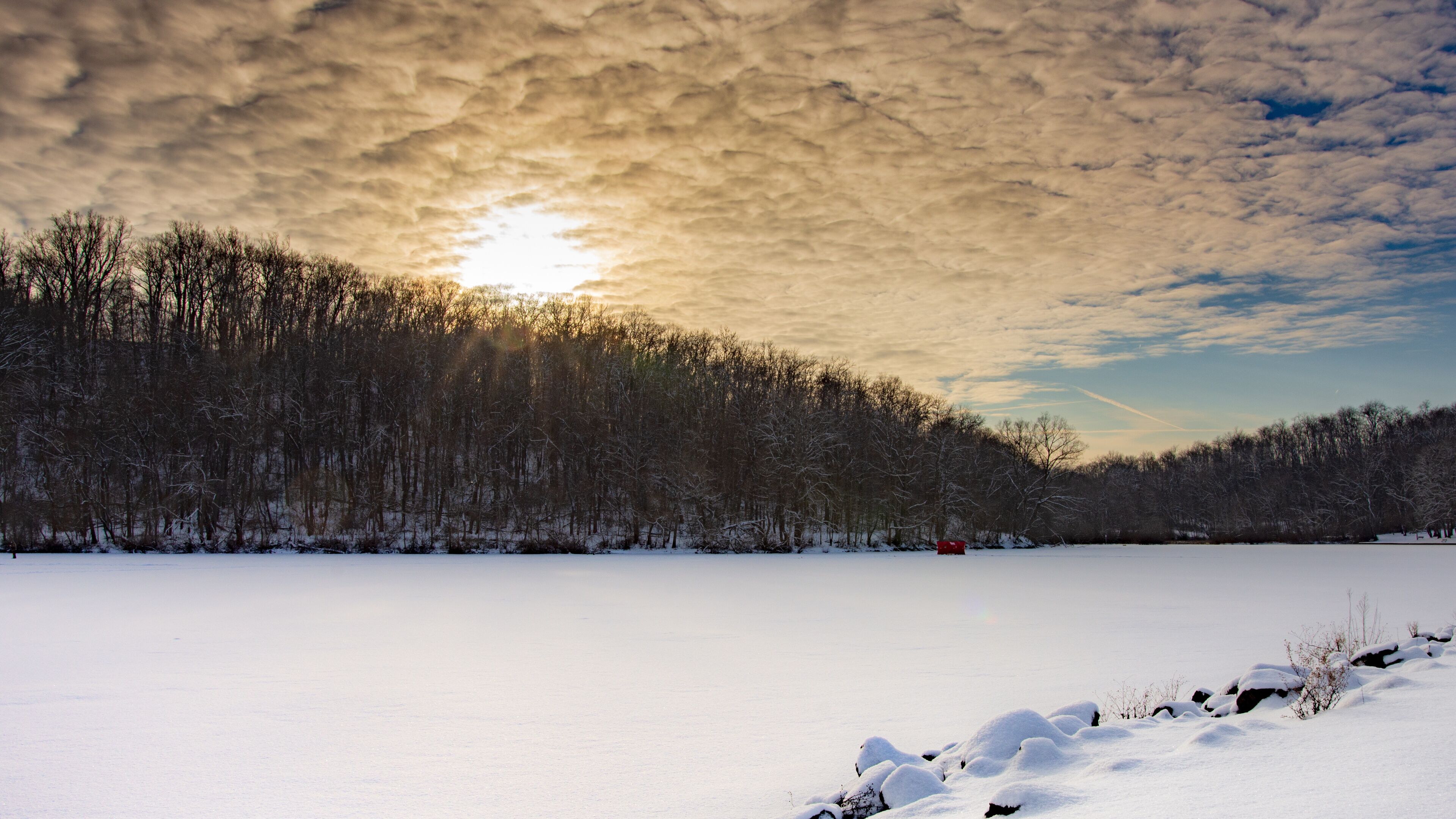 A snowy landscape with a forested hill and a clear sky.