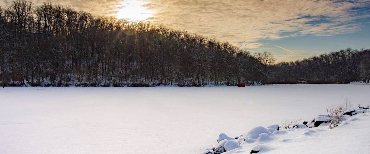 A snowy landscape with a forested hill and a clear sky.