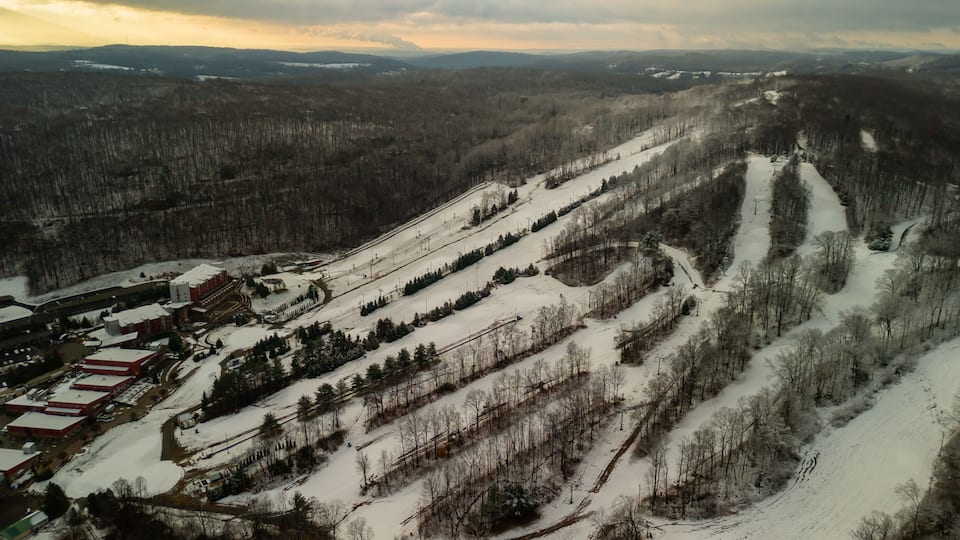 A snow-covered ski slope with a ski lift and buildings at the base.