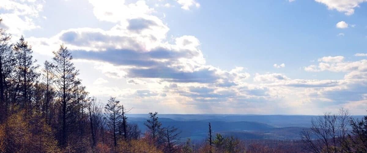 A mountainous landscape with autumn foliage and a partly cloudy sky.