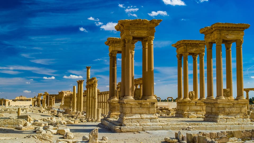 Ancient ruins with columns and stone structures under a clear blue sky.