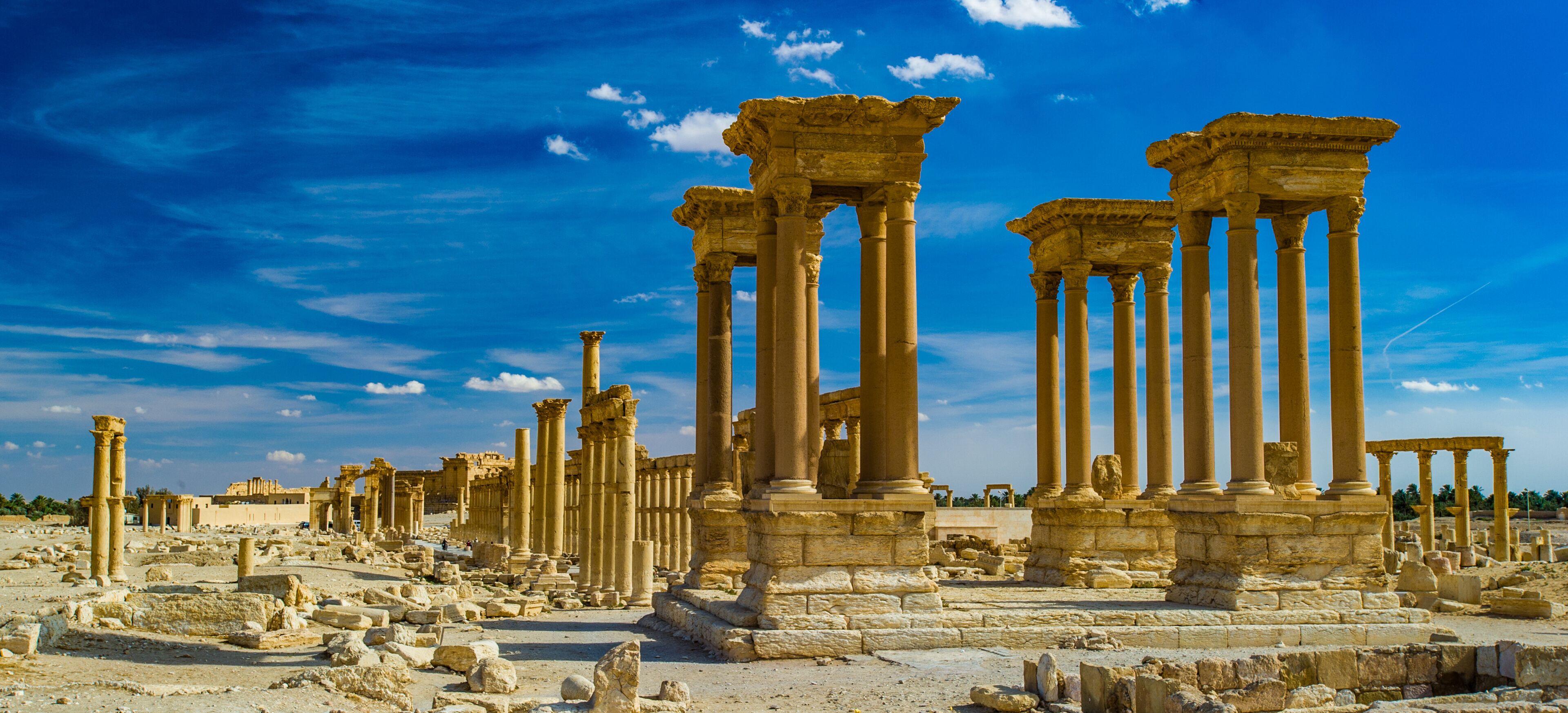 Ancient ruins with columns and stone structures under a clear blue sky.