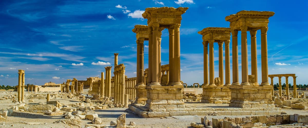 Ancient ruins with columns and stone structures under a clear blue sky.