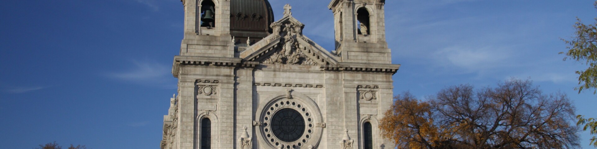 Una iglesia histórica grande con una cúpula destacada y dos torres de campanarios.