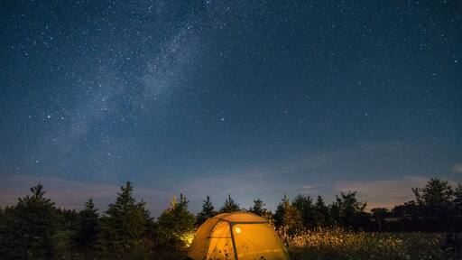 Illuminated camping tent under starry sky