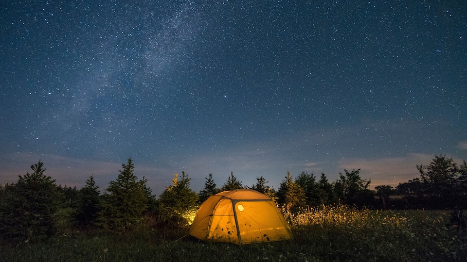 A tent under a starry night sky with a visible Milky Way.