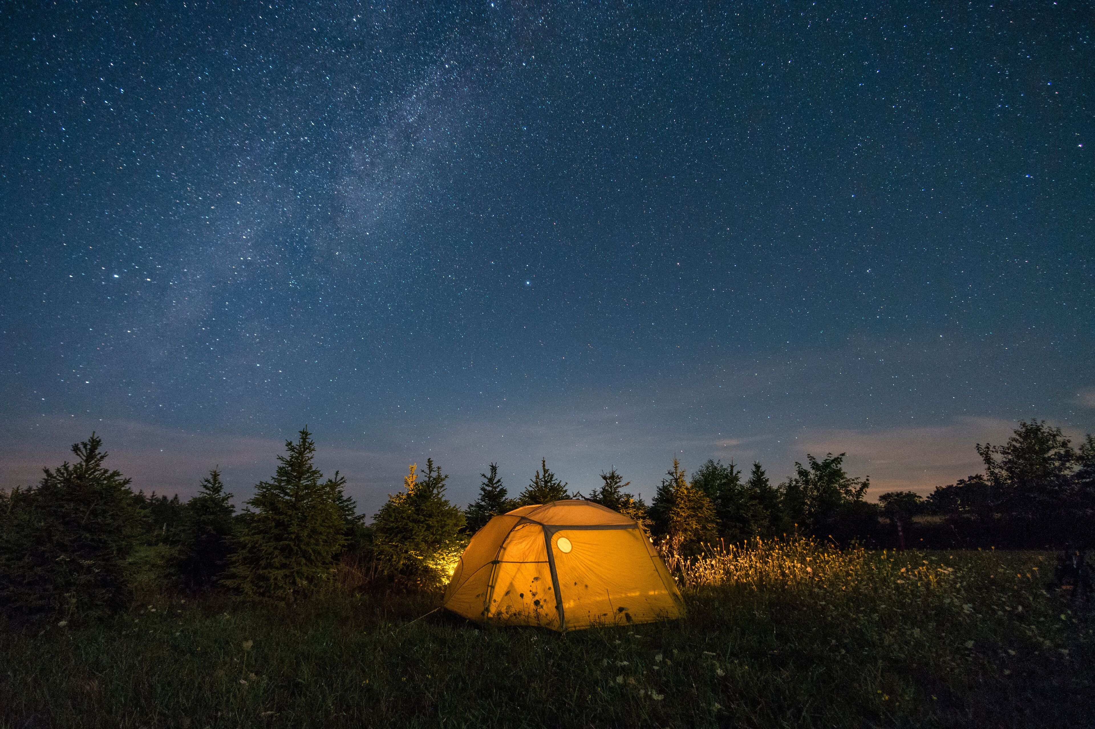 A tent under a starry night sky with a visible Milky Way.
