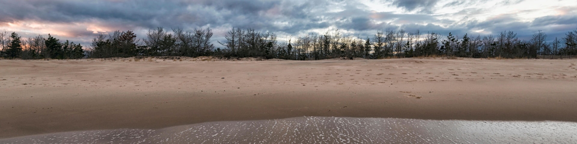 HG8DHK Waves reaching shore at beach against cloudy sky