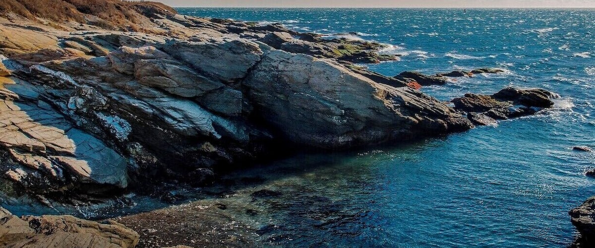 Beavertail Lighthouse, built in 1749, was and still is the premier lighthouse in Rhode Island, especially for entrance into Narragansett Bay.
From here, one could watch out and see the America's Cup races. 
This shot was taken late in the day, the warm glow of a setting sun lighting up the coastline.