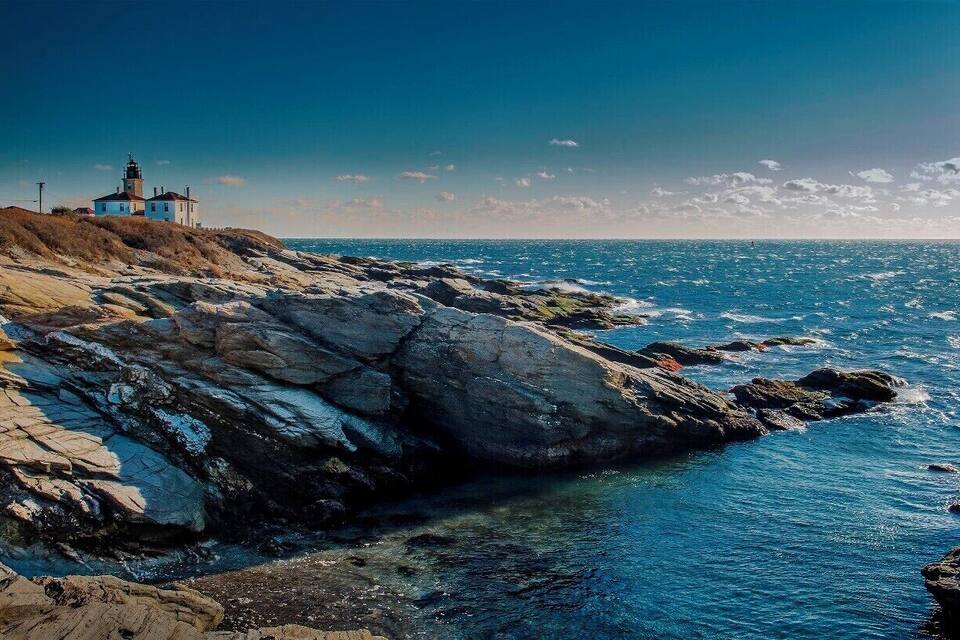 A lighthouse on a rocky coastline with clear blue waters.