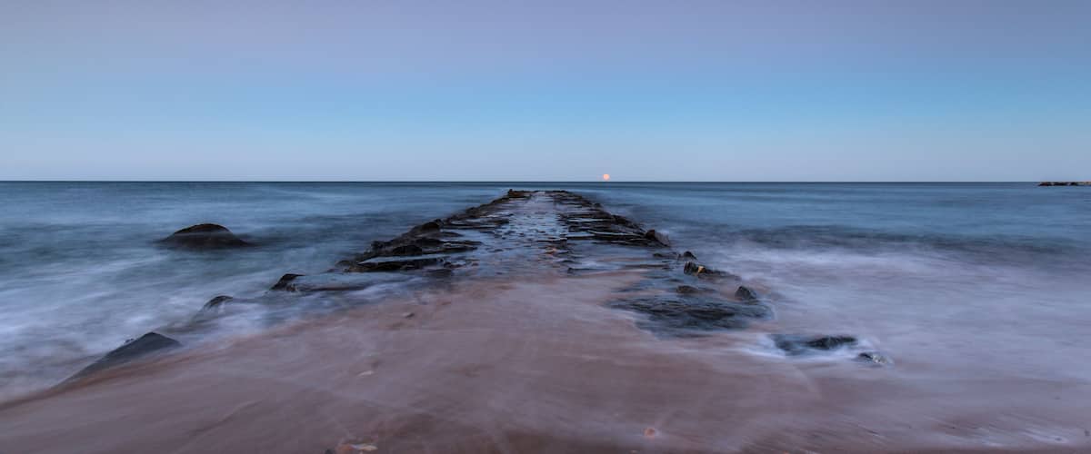 Een lange steiger die zich uitstrekt over rustig water, met een heldere lucht.