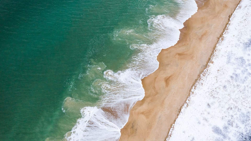 A sandy beach with clear turquoise water and gentle waves.