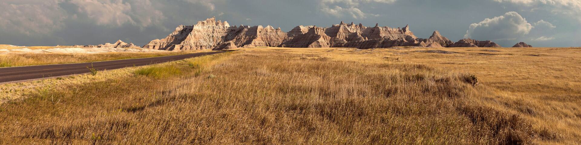 Panorama of badlands national park with vista of mountain range with large clouds in background