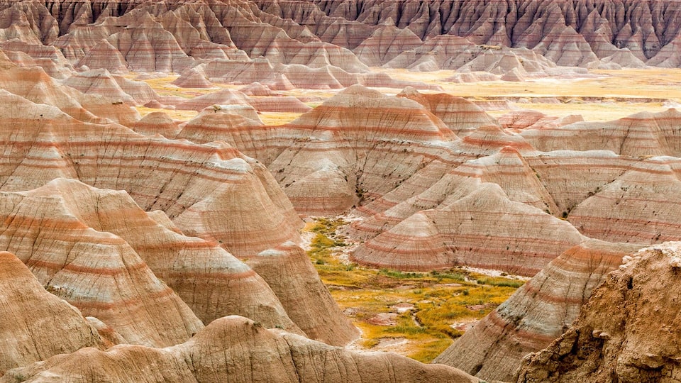 A landscape of eroded rock formations with layered colors and a valley in the background.
