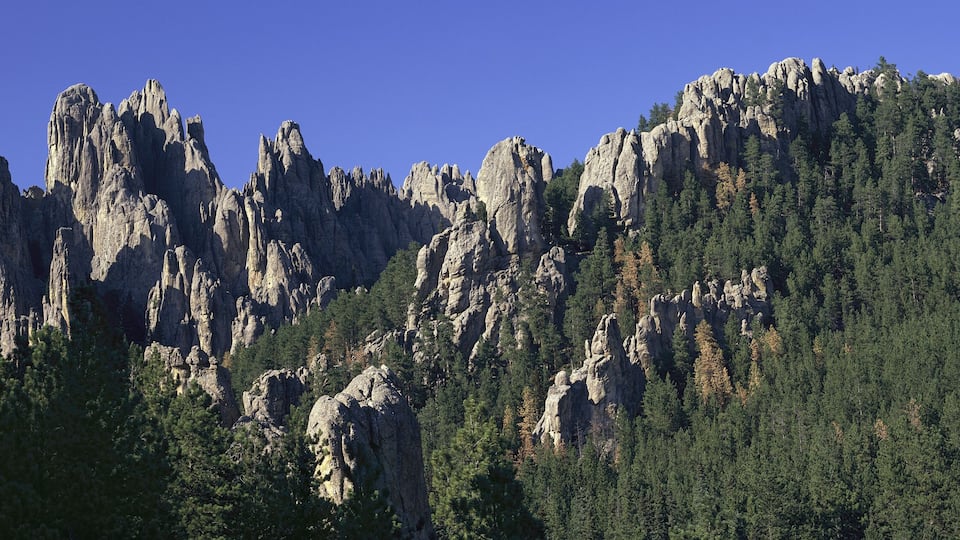 A rugged mountain range with prominent rock formations and dense forests.