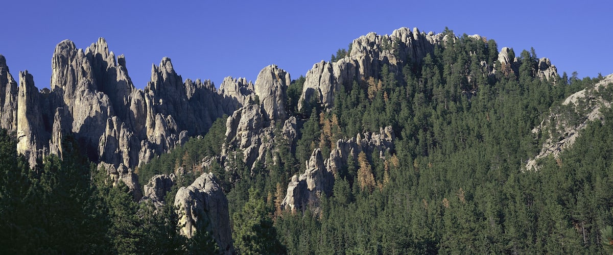 A rugged mountain range with prominent rock formations and dense forests.
