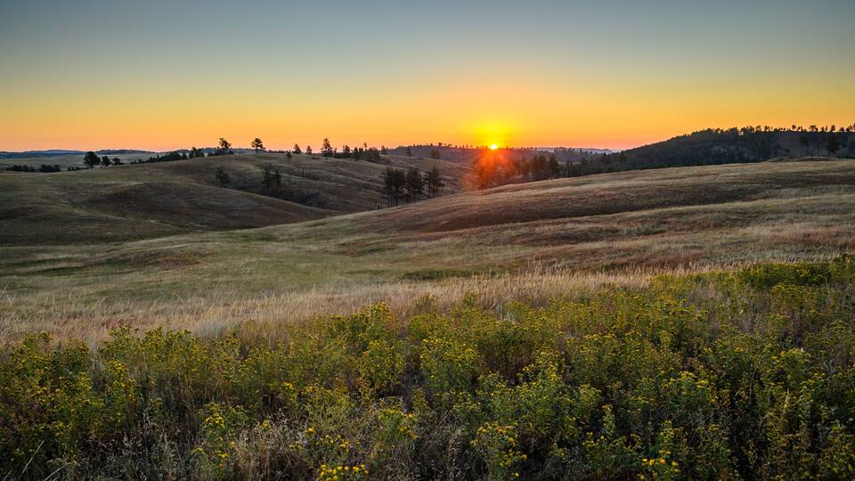 Rolling hills with a sunset in the background.