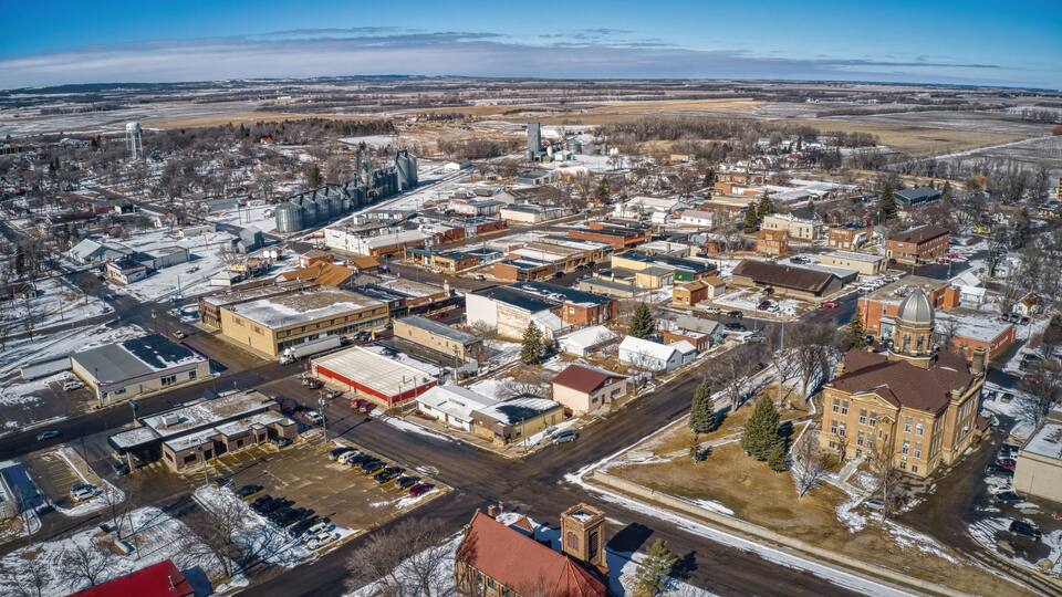 An aerial view of a town with industrial buildings, a large church, and snow-covered streets.