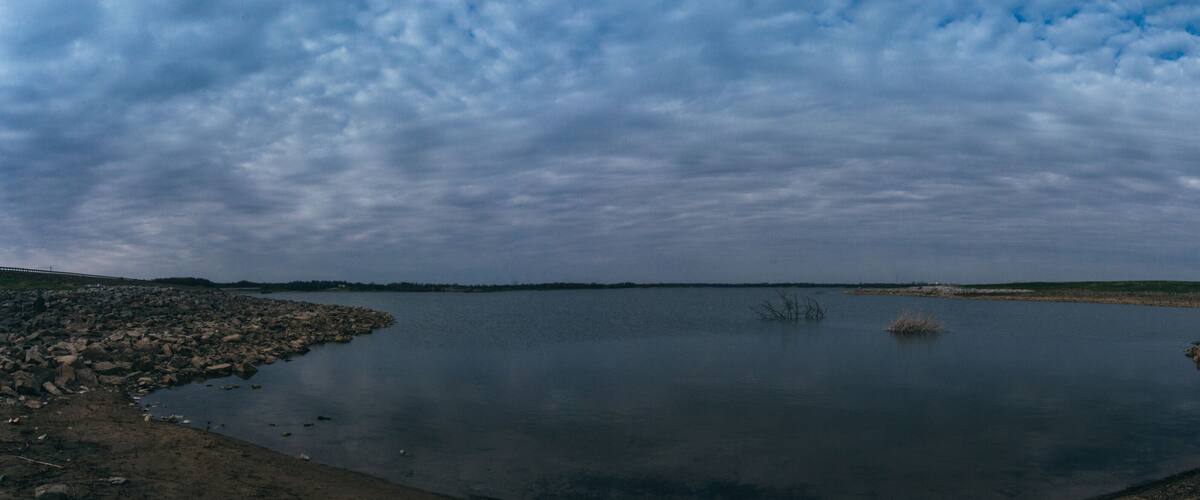A calm lake surrounded by rocky shores and a cloudy sky.