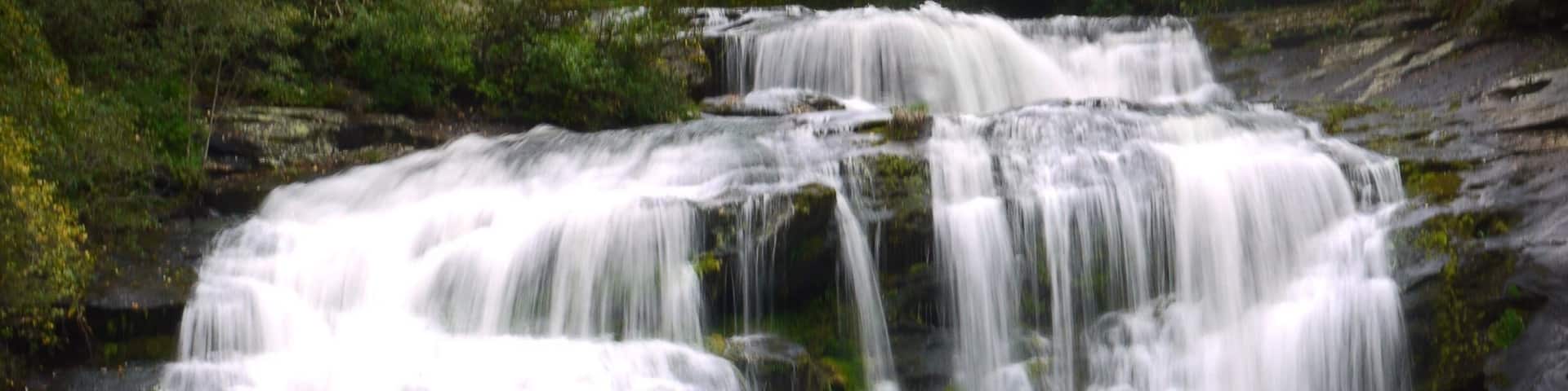 A multi-tiered waterfall surrounded by greenery.