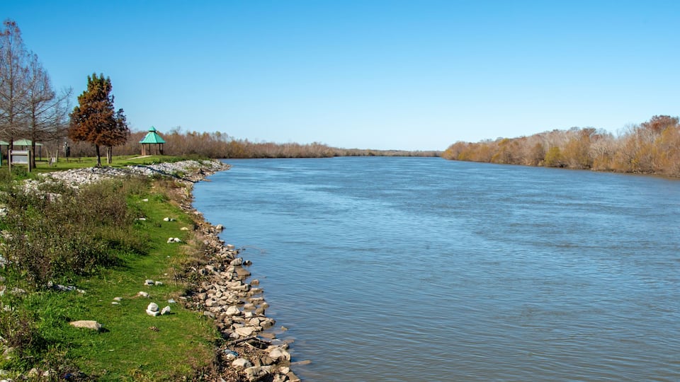 A river with a gazebo and a path along the bank.