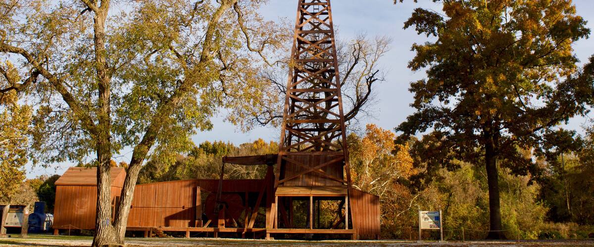 A tall metal tower with a wooden structure at its base, surrounded by autumn-colored trees.