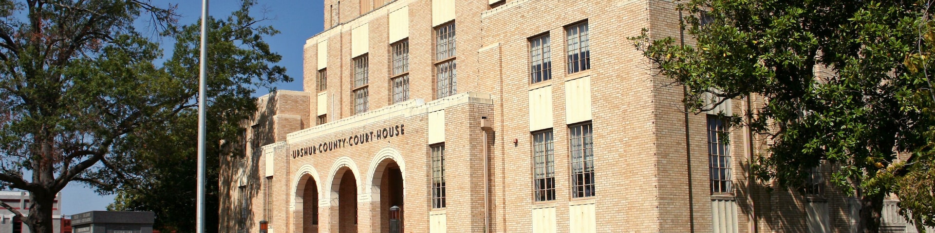 A courthouse with a Texas flag, brick architecture, and a well-maintained lawn.