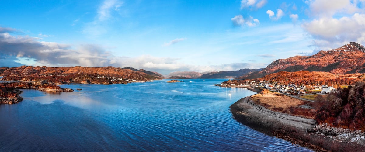 A coastal town with a bay, mountains, and a bridge.