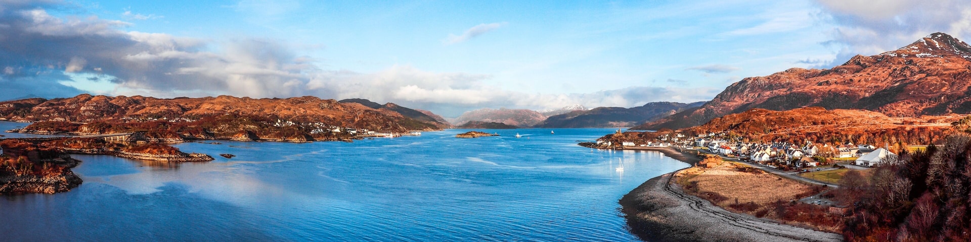 A coastal town with a bay, mountains, and a bridge.