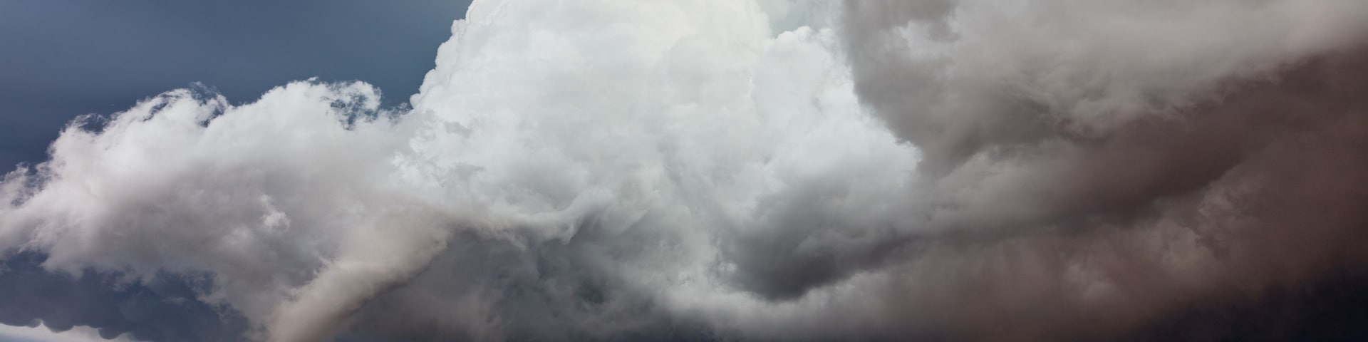 A vast, barren landscape under a dramatic sky with large, dark storm clouds.