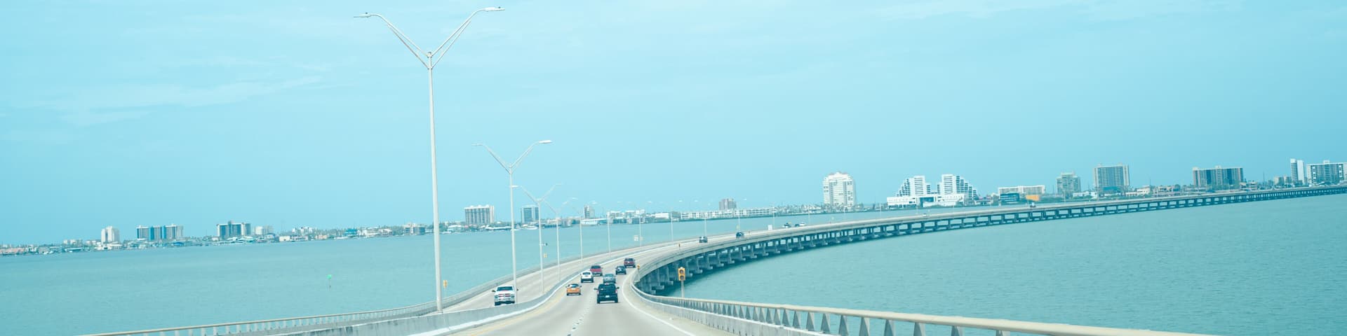Panorama view Queen Isabella Memorial Bridge Causeway over Gulf Coast and South Padre Island buildings background, concrete pier-and-beam bridge, steel cantilever main beam span from Port Isabel