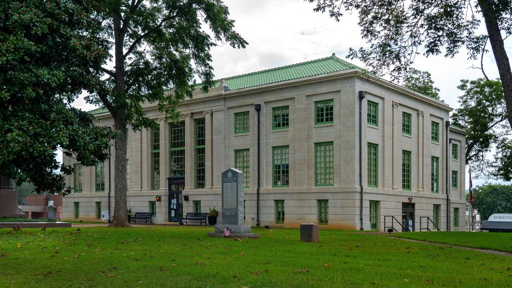 A large, historic building with green-framed windows and a green roof.